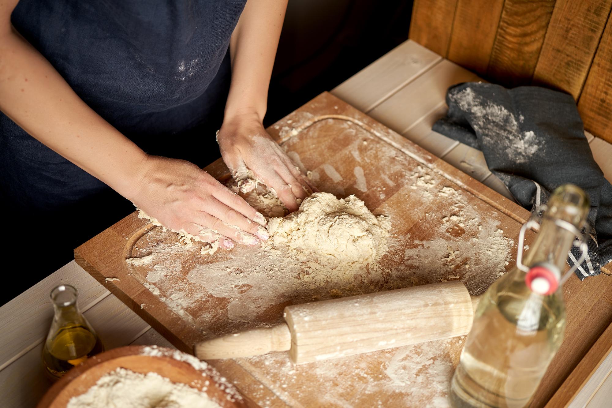 hands shaping sourdough on wooden board